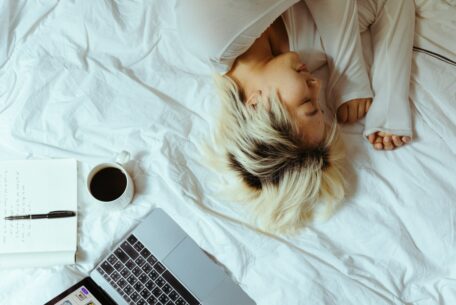 Lazy afternoon as a mom- woman lying on her bed with open laptop and coffee cup