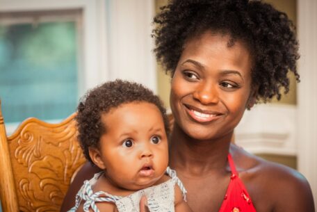 woman in orange shirt carrying baby in white top: myths about life after pregnancy