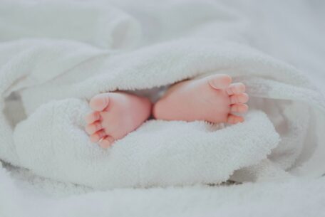 Barefooted baby toes in white blanket: preparing for a baby