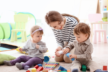 babysitter playing on the floor with two children: reasons to hire a babysitter