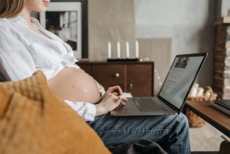 Pregnant woman sitting on couch using a laptop: postpartum PTSD