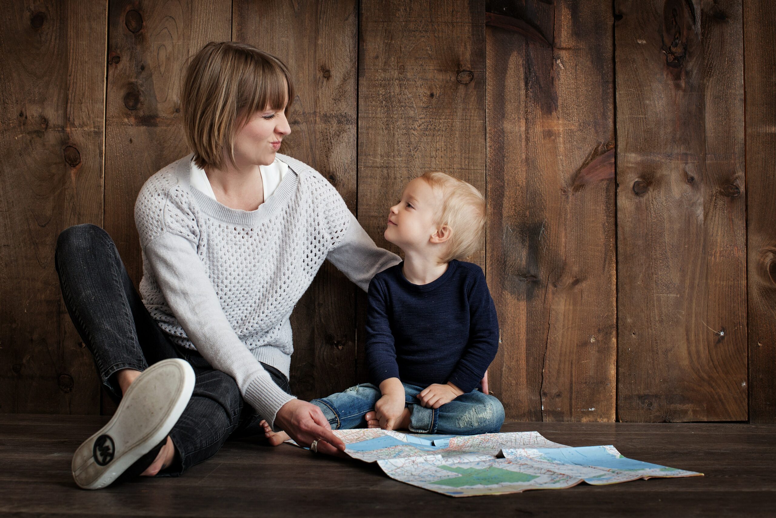 Mom sitting with child on the ground with a map: enjoy mom life