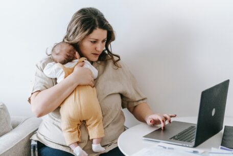 Mom working on laptop while holding infant: build a thriving business
