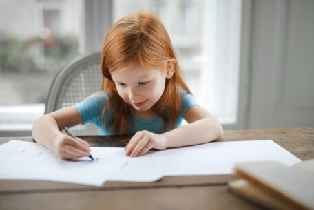 Girl drawing on paper at a table: help kids with learning