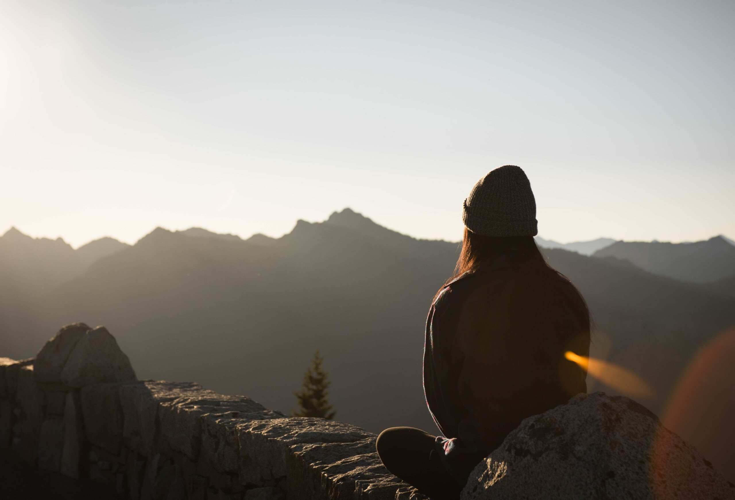 Person sitting on top of mountain ruminating